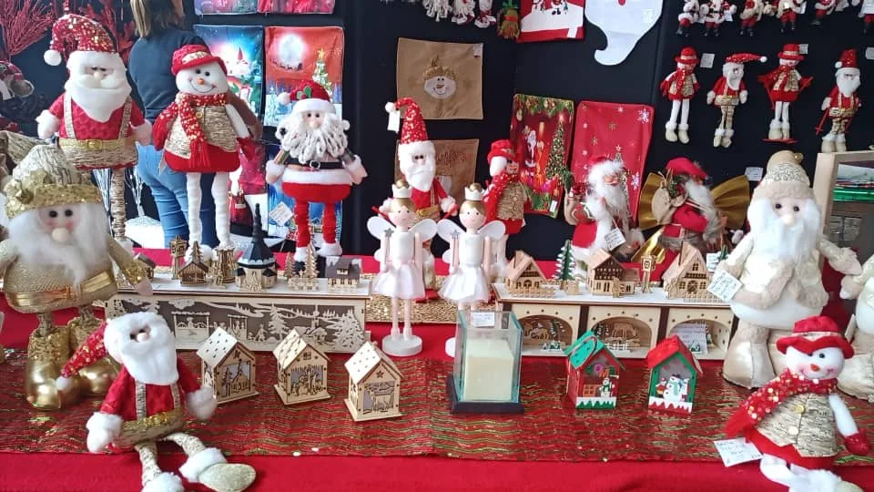 Casa Enrique Christmas decor: Santas, angels, and wooden houses on a red table.