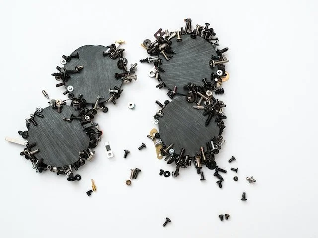 Circular magnets covered in screws and small metal hardware.